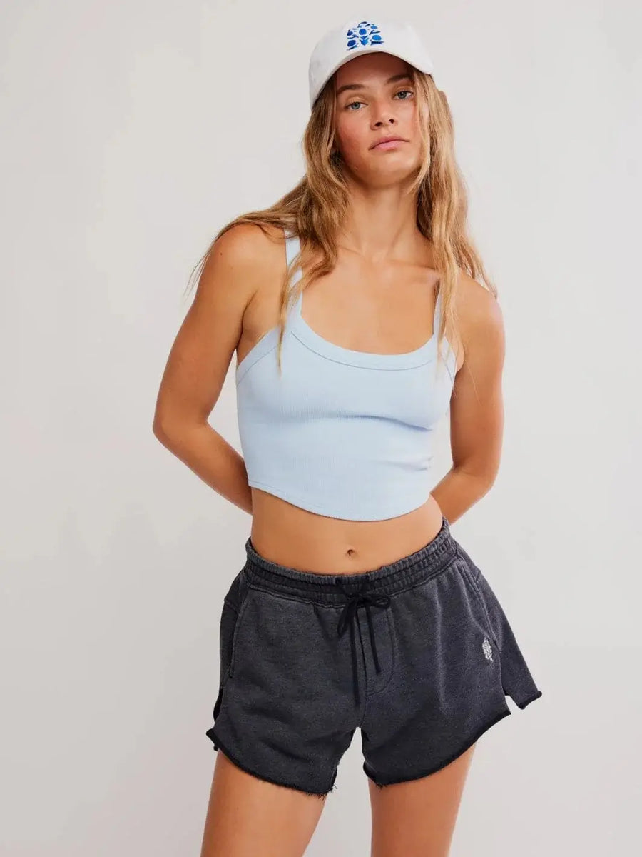 A front view showcases the relaxed fit, drawstring waistband, and raw-edge hems of the Free People Knockout Short in Black styled with a light blue tank top | Twentyseven Toronto