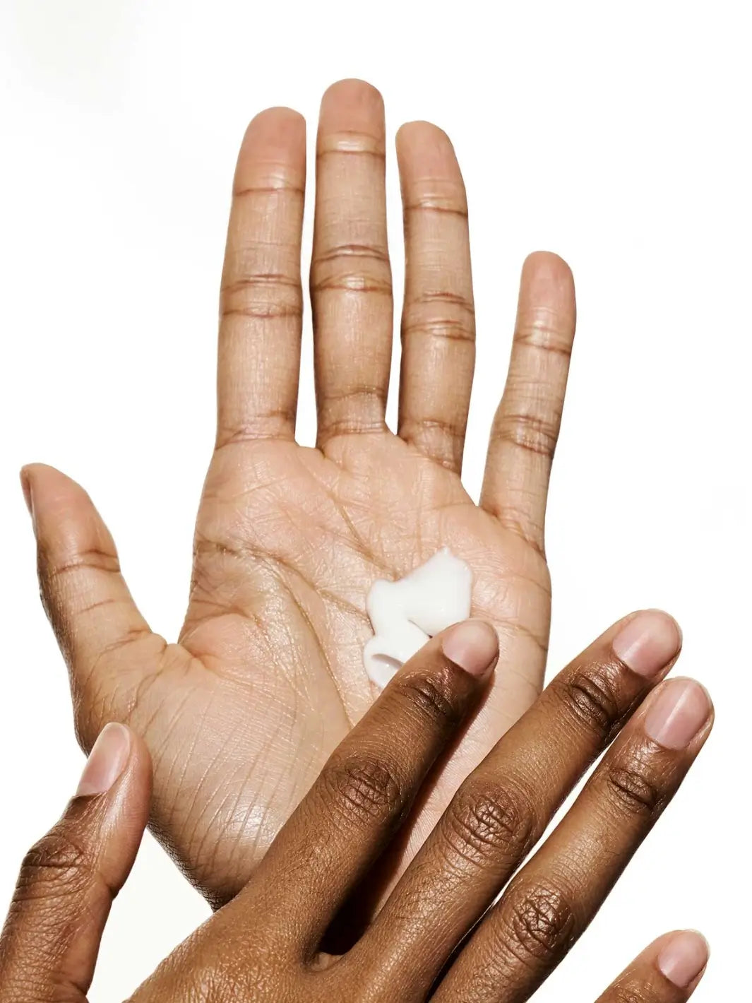 Two hands showing texture of white cream, using La Crème All-in-One Daily Moisturizer from Doré Skincare against a white background | Twentyseven Toronto