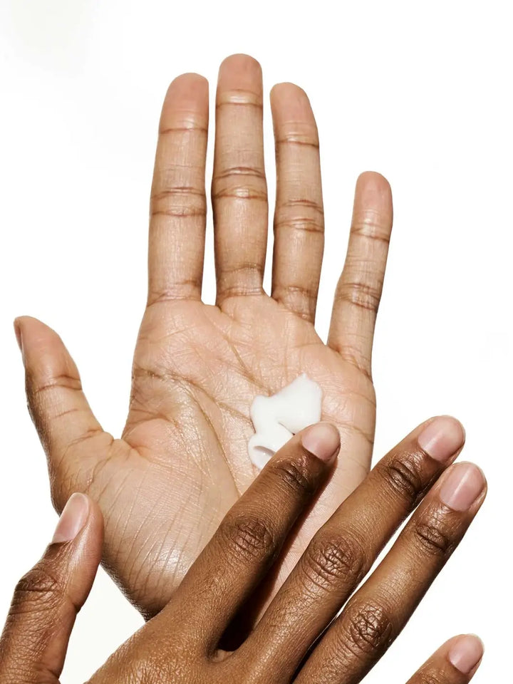 Two hands showing texture of white cream, using La Crème All-in-One Daily Moisturizer from Doré Skincare against a white background | Twentyseven Toronto