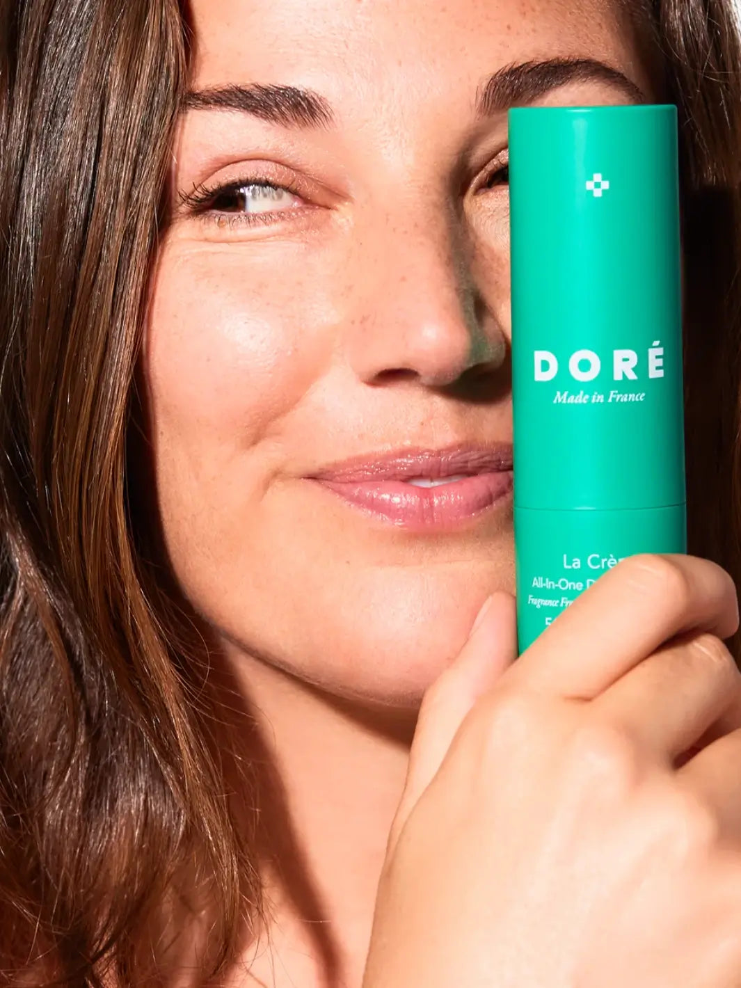 Woman holding a green bottle of Doré Skincare 'La Crème All-in-One Daily Moisturizer' | Twentyseven Toronto