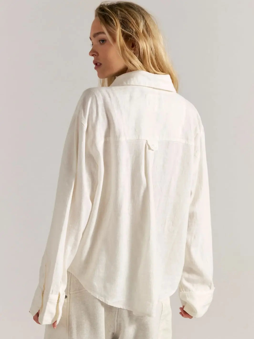 Woman wearing a white button down shirt by Free People We the Free 'Laurel Linen Button Down Top' in 'Clean Ivory' against white background, back view | Twentyseven Toronto