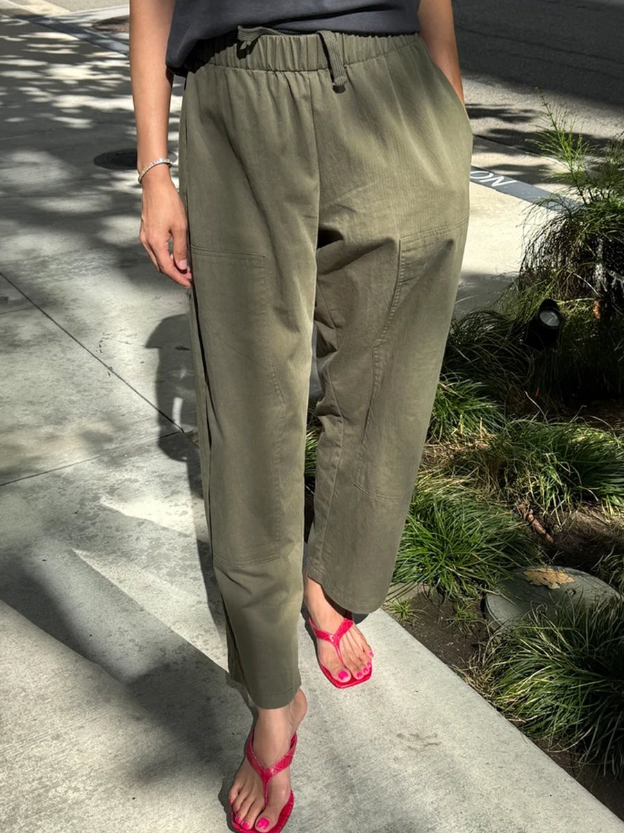 Gardener’s Pants in Army Green styled with a black top and red sandals, showing the relaxed tapered fit, drawstring waist, and carpenter-inspired front pockets | Twentyseven Toronto
