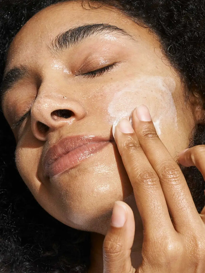 Close-up of person applying white foamy Doré Skincare 'Le Cleanser' to their face | Twentyseven Toronto