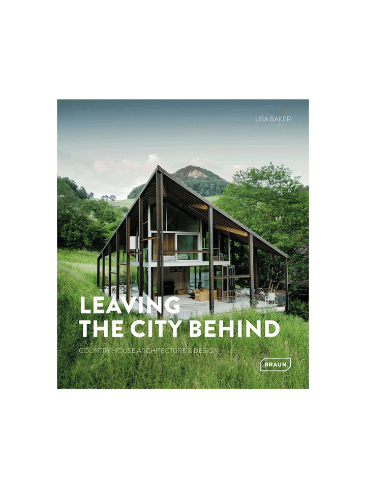 Book cover for 'Leaving the City Behind: Country House Architecture & Design' by Lisa Baker, featuring a large modern open-frame house with a steep gable roof in a grassy, mountainous landscape | Twentyseven Toronto