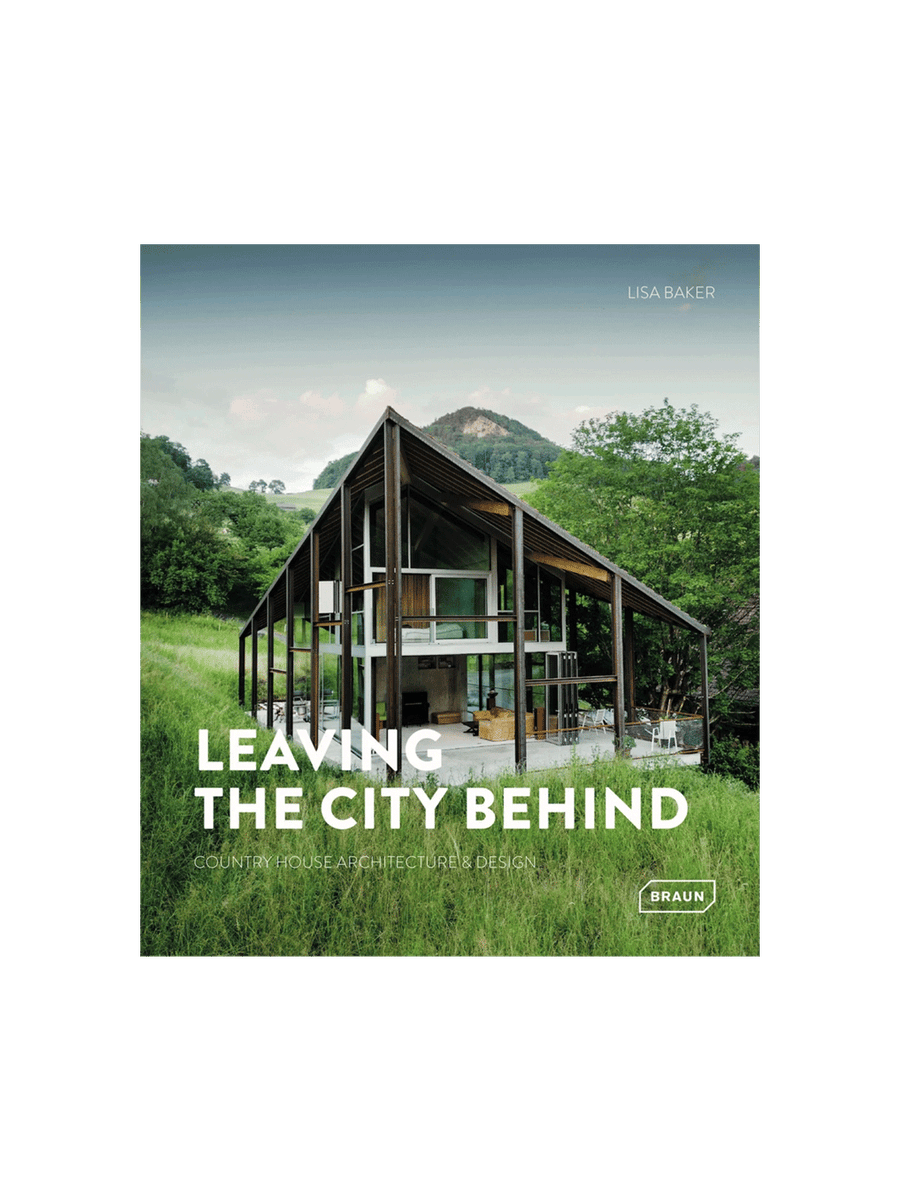 Book cover for 'Leaving the City Behind: Country House Architecture & Design' by Lisa Baker, featuring a large modern open-frame house with a steep gable roof in a grassy, mountainous landscape | Twentyseven Toronto