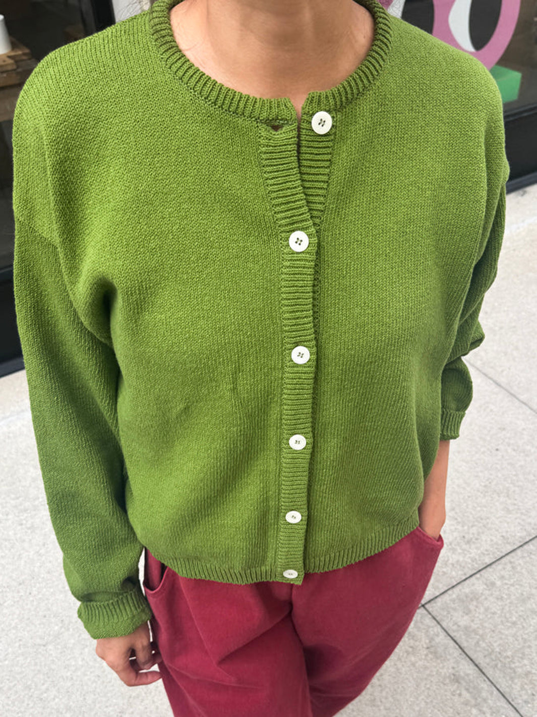 Front view of the Leila Cotton Cardigan in Avocado, styled with burgundy pants | Twentyseven Toronto