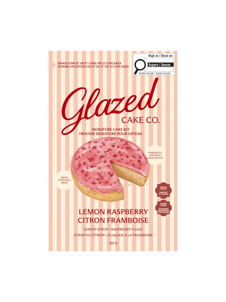 The front of a pink and cream striped box displays the product packaging for the Glazed Cake Co Lemon Raspberry Cake Kit with an illustration of a sliced lemon cake | Twentyseven Toronto