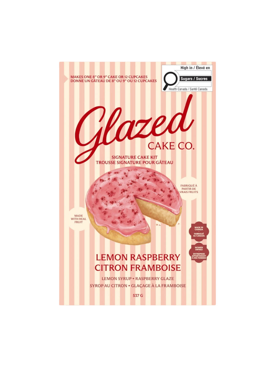 The front of a pink and cream striped box displays the product packaging for the Glazed Cake Co Lemon Raspberry Cake Kit with an illustration of a sliced lemon cake | Twentyseven Toronto