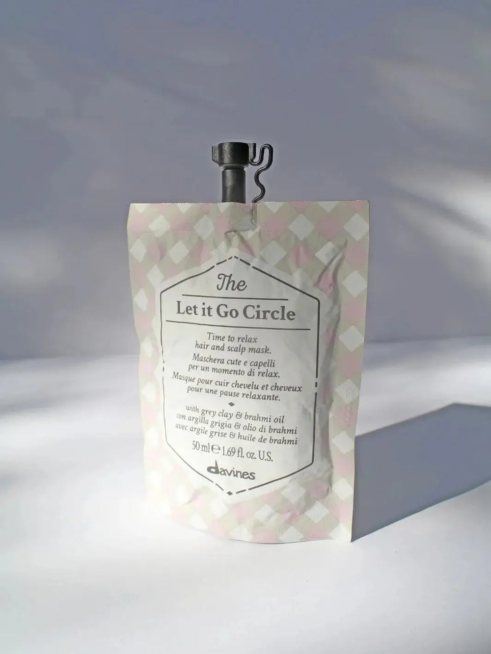 A single pouch of Davines Let it Go Circle of Chronicles Hair Mask with a pink and grey checkered pattern against a white background | Twentyseven Toronto