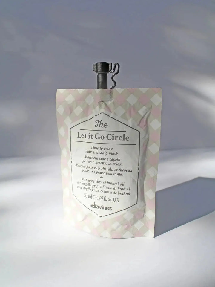 A single pouch of Davines Let it Go Circle of Chronicles Hair Mask with a pink and grey checkered pattern against a white background | Twentyseven Toronto