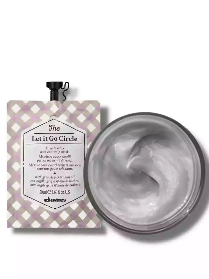 A checkered pouch of Davines Let it Go Circle of Chronicles Hair Mask is displayed next to an open jar filled with swirling grey cream | Twentyseven Toronto