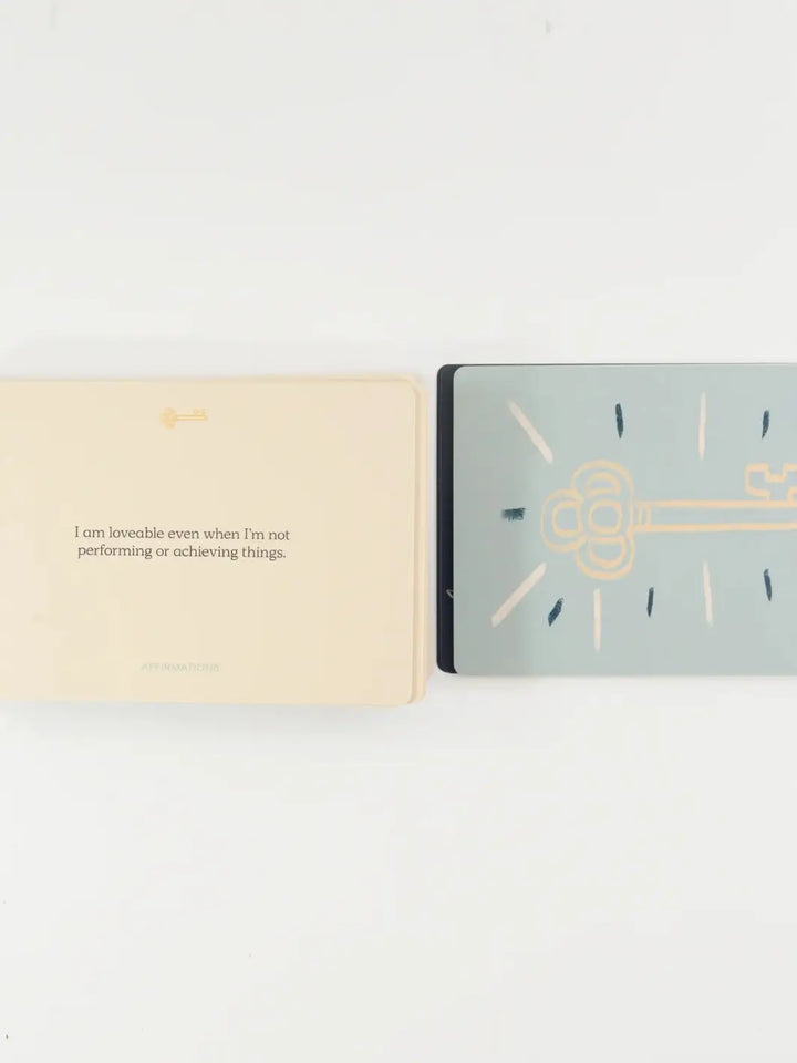 An affirmation card reading "I am loveable even when I'm not performing or achieving things" lies next to a gold key graphic from the Letting Your Shadow In Deck from People I've Loved | Twentyseven Toronto