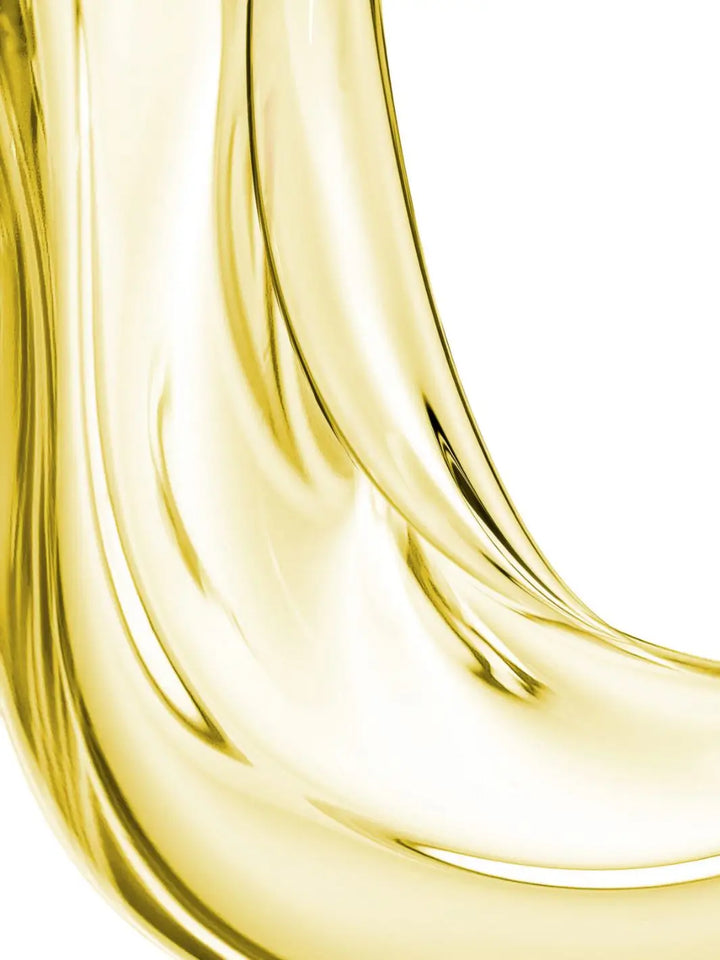 Close-up of 'L’Huile de Leonor Greyl' gold liquid with a white background | Twentyseven Toronto
