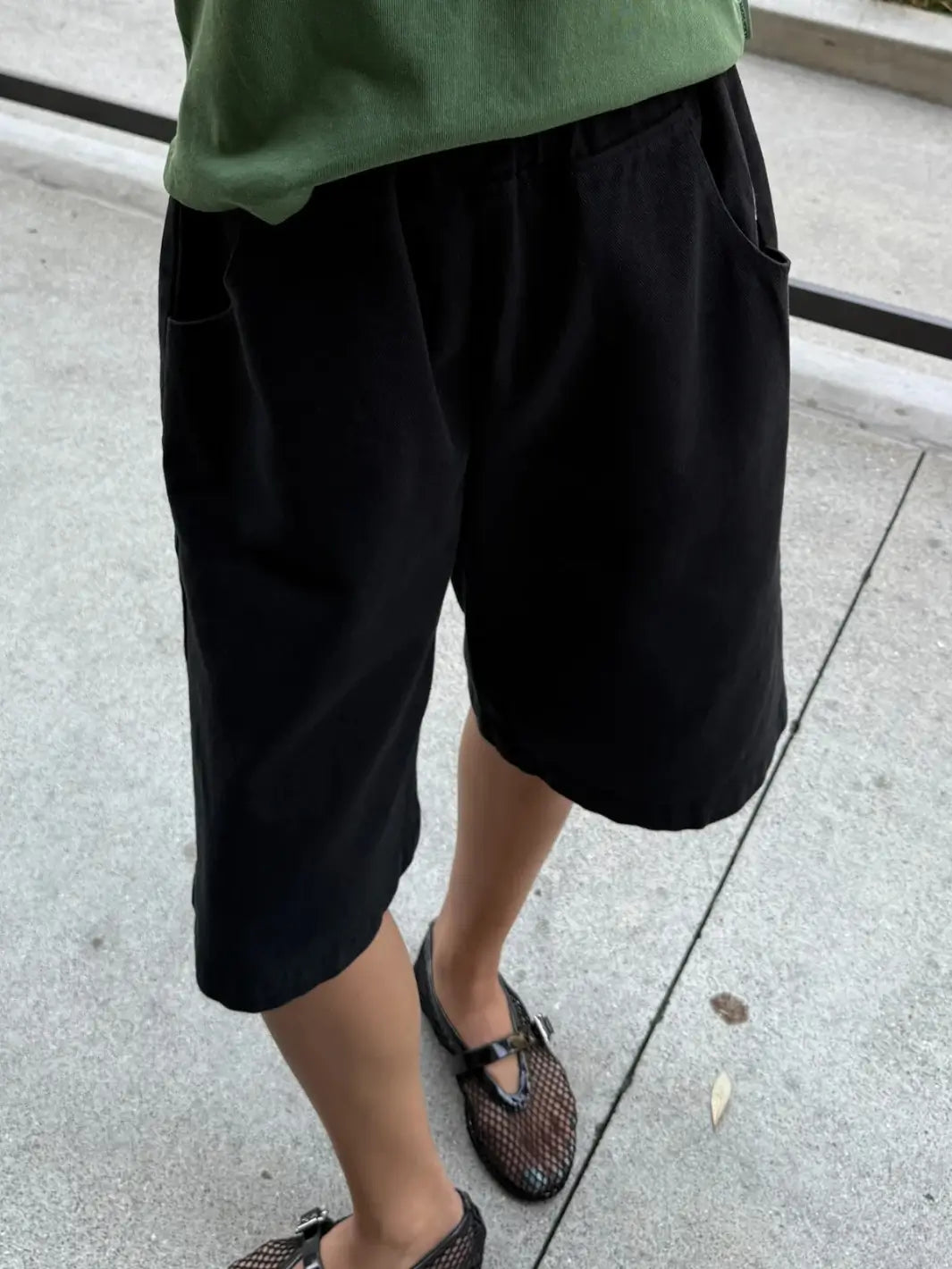 A close-up shot focuses on the durable canvas fabric texture and wide-leg opening of the Le Bon Shoppe Liam Bermuda Shorts - Black Canvas | Twentyseven Toronto