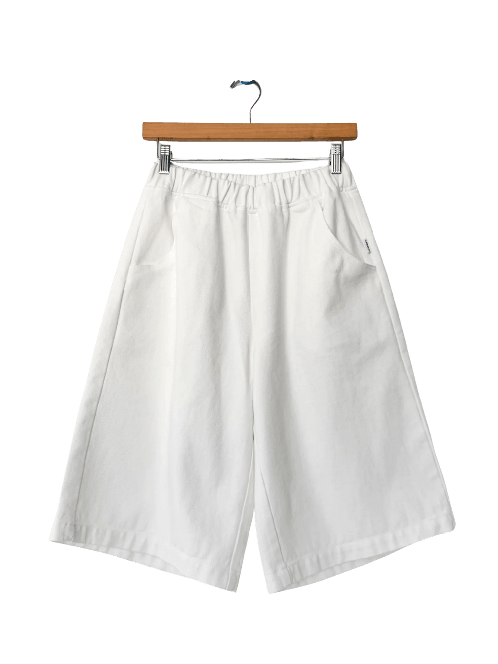 The off-white Le Bon Shoppe Liam Bermuda Shorts - Milk are displayed flat on a wooden clip hanger | Twentyseven Toronto