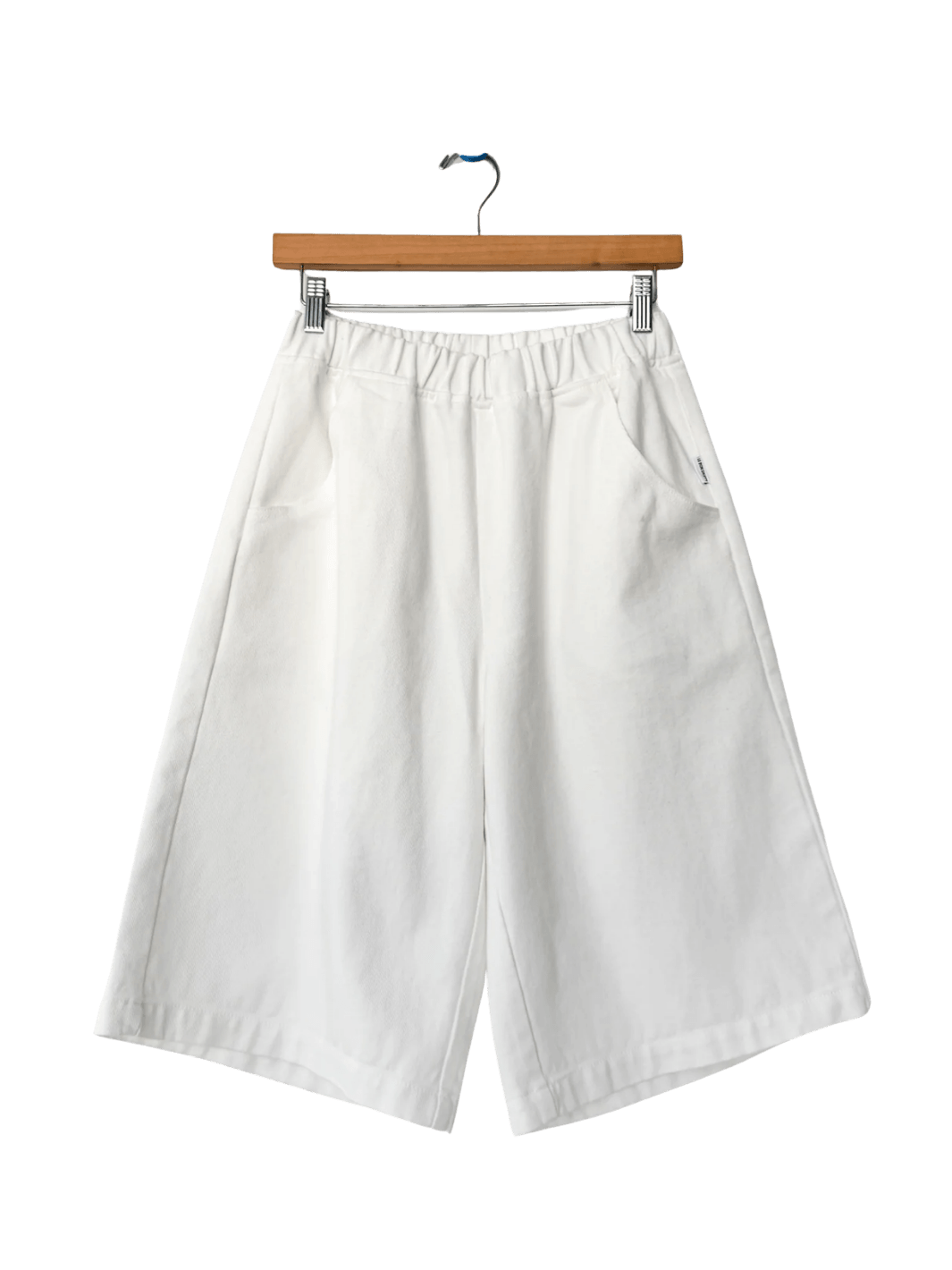 The off-white Le Bon Shoppe Liam Bermuda Shorts - Milk are displayed flat on a wooden clip hanger | Twentyseven Toronto