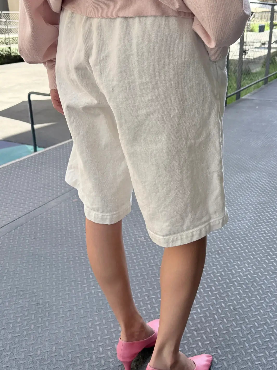 A rear-view shot highlights the high-waisted fit, elastic waistband, and textured canvas material of the Le Bon Shoppe Liam Bermuda Shorts - Milk | Twentyseven Toronto