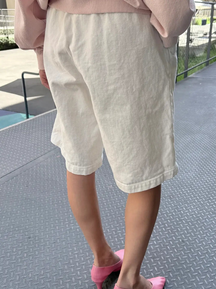 A rear-view shot highlights the high-waisted fit, elastic waistband, and textured canvas material of the Le Bon Shoppe Liam Bermuda Shorts - Milk | Twentyseven Toronto