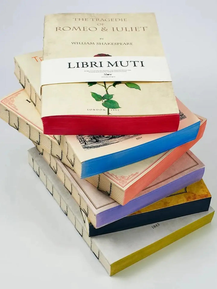 A stacked arrangement of notebooks from the Slow Design Libri Muti collection features exposed, hand-stitched spines and vibrantly coloured, hand-painted edges | Twentyseven Toronto