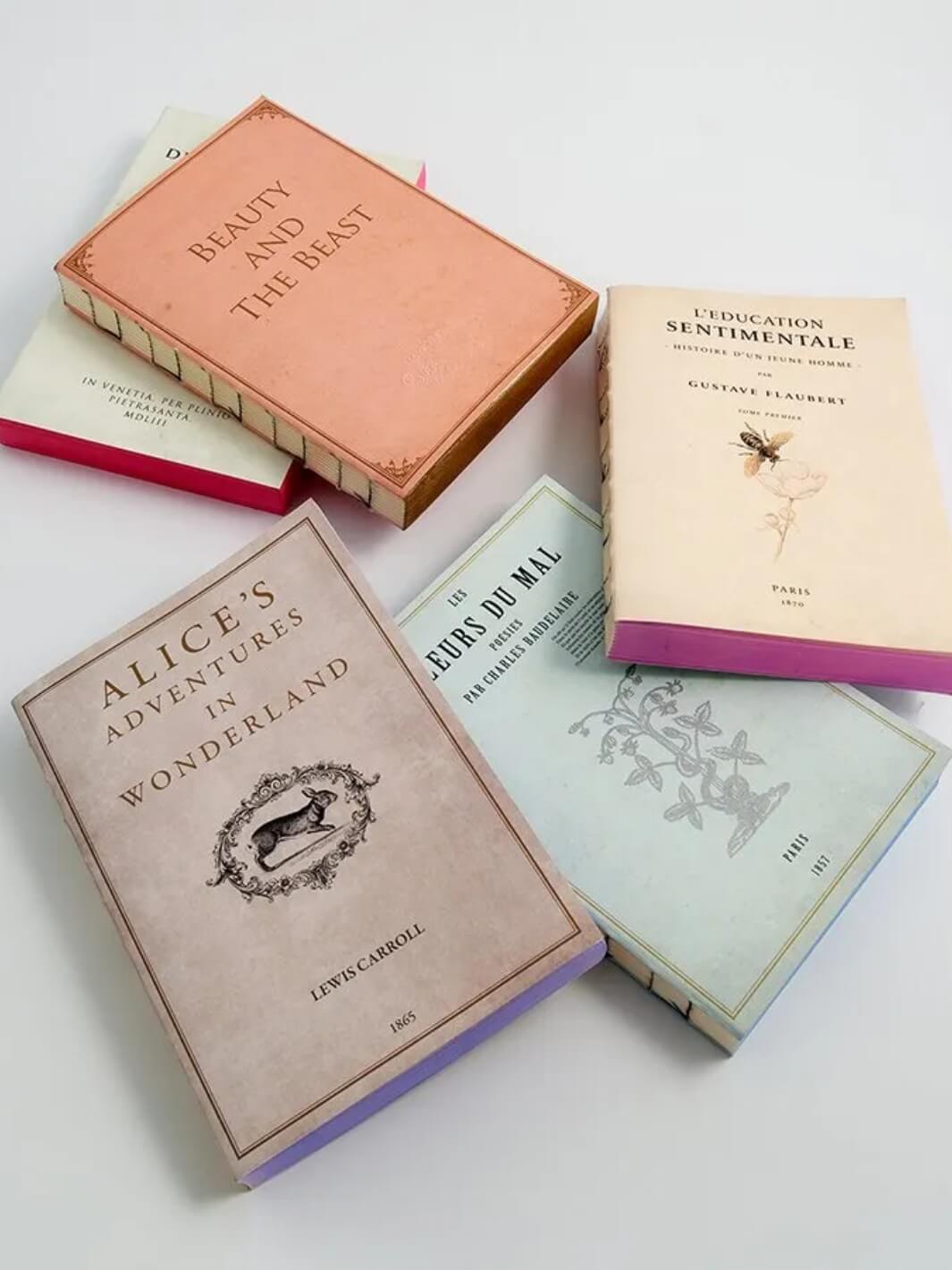 A collection of vintage-style notebooks lies scattered on a white surface from the Slow Design Libri Muti collection | Twentyseven Toronto