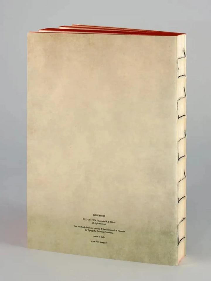 The back cover of a Jungle Book notebook from the Slow Design Libri Muti collection shows a clean, cream-colored surface with small publishing details at the bottom, an exposed hand-stitched spine, and orange hand-painted edges along the top | Twentyseven Toronto