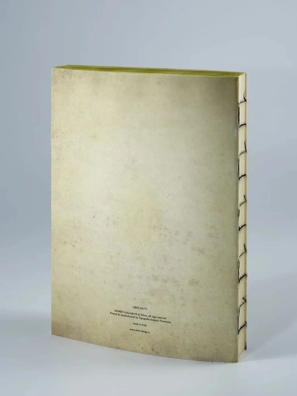 The cream-colored back cover of an exposed-stitch notebook features small text at the bottom identifying it as part of the Les Reveries from the Slow Design Libri Muti collection, handcrafted by Tipografia Artistica Fiorentina in Italy | Twentyseven Toronto
