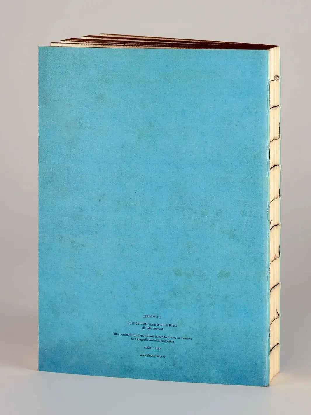 The back cover of a light blue, exposed-stitch notebook features small printed text at the bottom detailing the Once Upon A Time from the Slow Design Libri Muti collection, handcrafted in Florence, Italy | Twentyseven Toronto