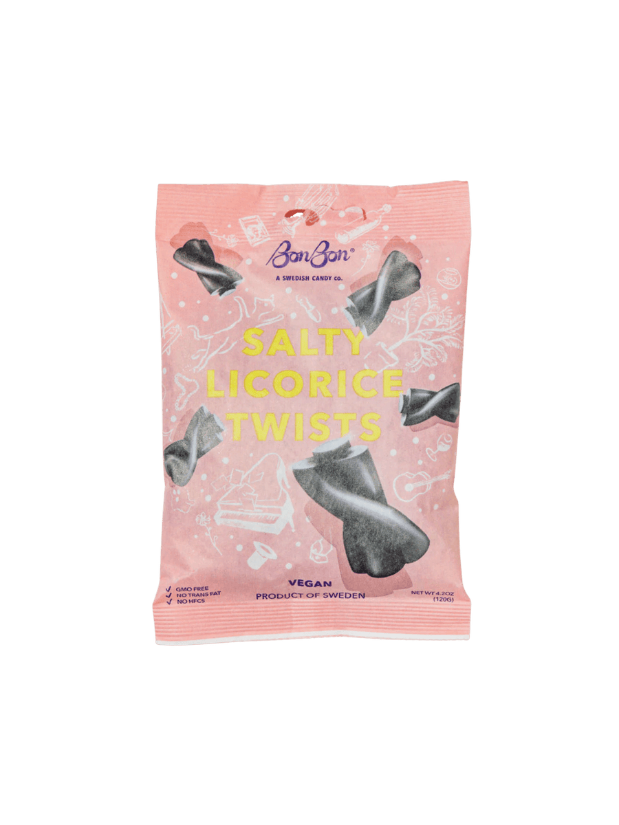 A sealed pink pouch featuring illustrations of floating black candies showcases the front packaging of Licorice Twist Swedish Candy from BonBon NYC against a transparent background | Twentyseven Toronto
