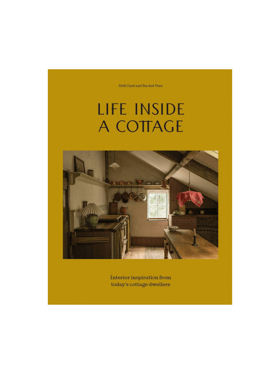 Book cover for Life Inside A Cottage by Nell Card and Rachel Vere features a mustard-yellow background with a central photo of a cozy, low-ceilinged cottage kitchen filled with copper pots and rustic charm | Twentyseven Toronto