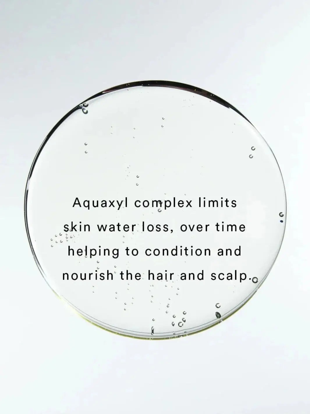 Black text overlaid on a clear, round droplet describes how the Aquaxyl complex in Hair by Sam McKnight Light Cleanse Hair & Scalp Shampoo limits water loss to condition the scalp | Twentyseven Toronto