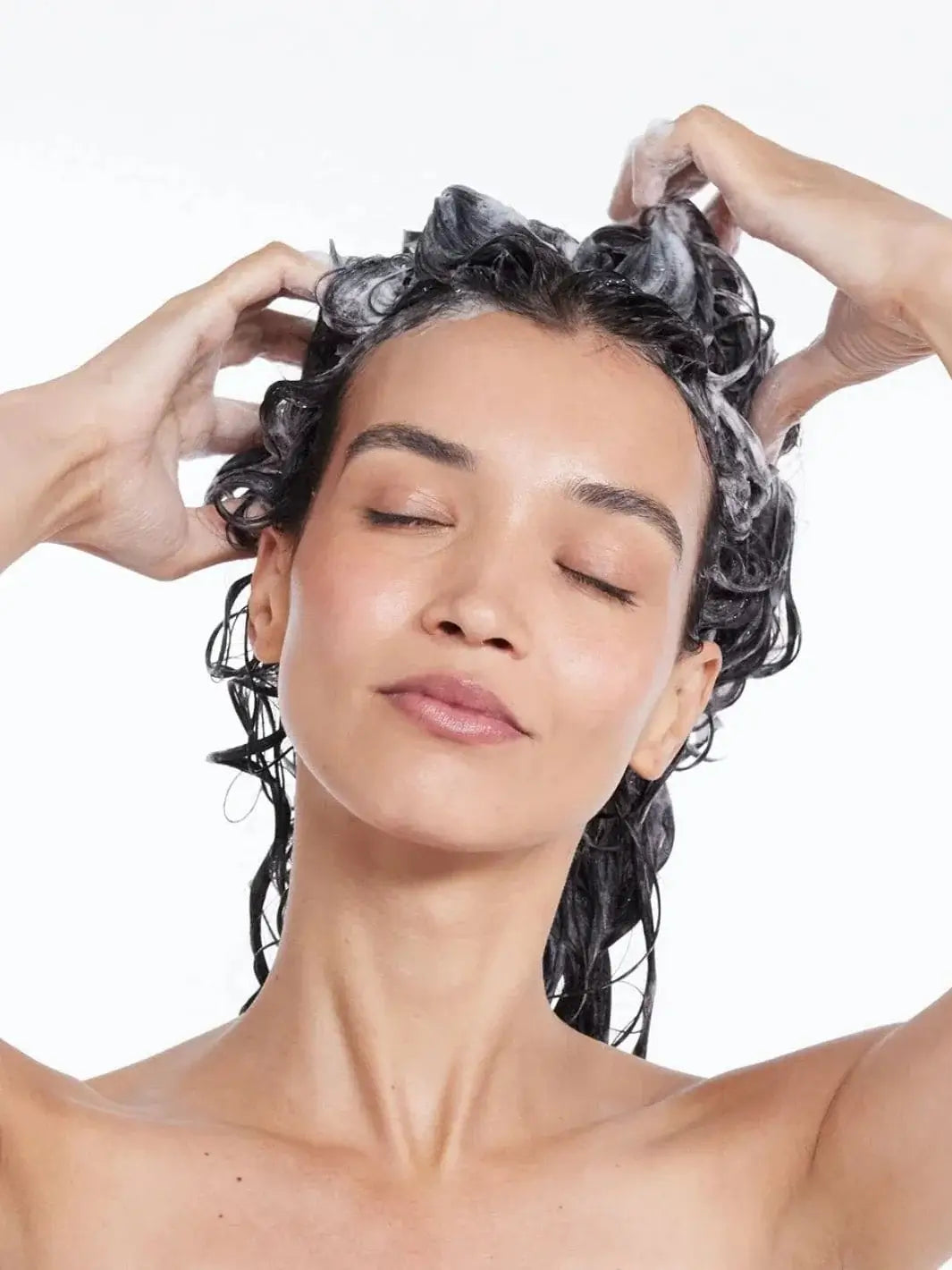A woman closes her eyes as she massages a rich, foamy lather into her hair while washing with Hair by Sam McKnight Light Cleanse Hair & Scalp Shampoo | Twentyseven Toronto