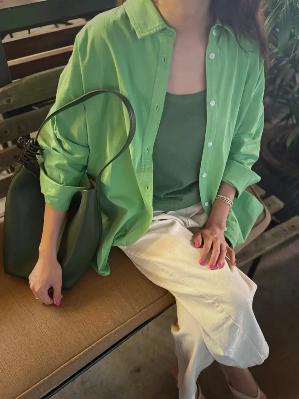 Person wearing a 'Light Weight Owen Shirt' in 'Green Bud' from Le Bon Shoppe and white pants sitting on a bench | Twentyseven Toronto