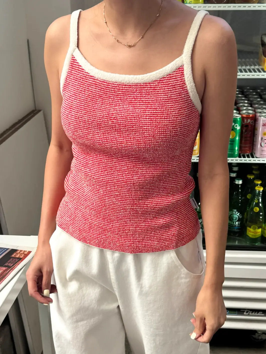 Person wearing a red 'Lily Sweater Cami' tank top in 'Red Stripe' design with white trim from Le Bon Shoppe in a store setting | Twentyseven Toronto