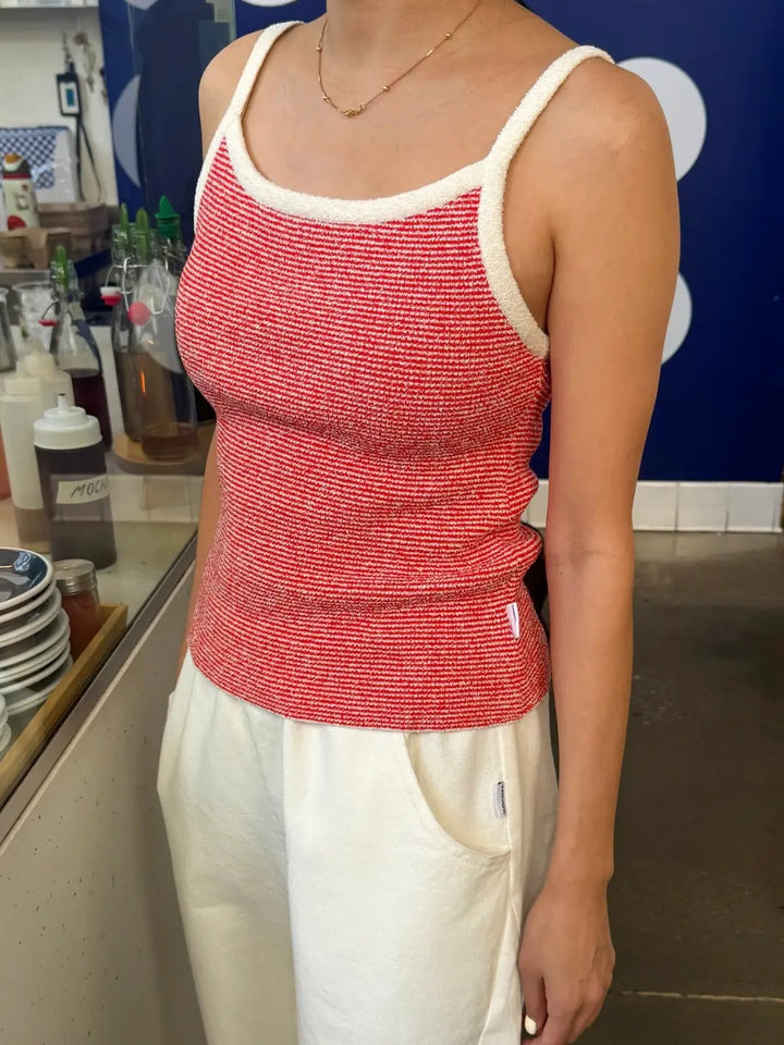Person wearing a red 'Lily Sweater Cami' tank top in 'Red Stripe' design with white trim from Le Bon Shoppe in a store setting | Twentyseven Toronto