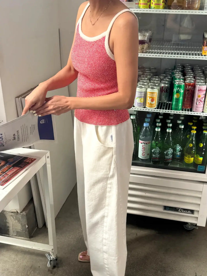 Person wearing a red 'Lily Sweater Cami' tank top in 'Red Stripe' design with white trim from Le Bon Shoppe in a store setting | Twentyseven Toronto