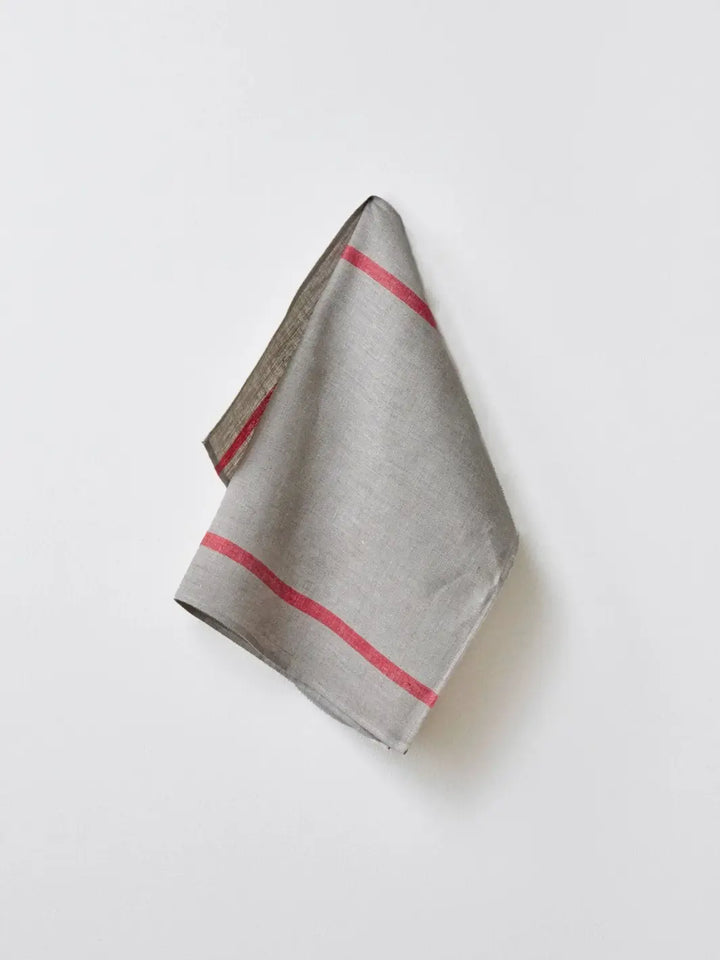 The Lined Kitchen Cloth - Natural with Red Stripe from Fog Linen Work is shown hanging elegantly against a neutral wall, displaying its stripe detail | Twentyseven Torotno