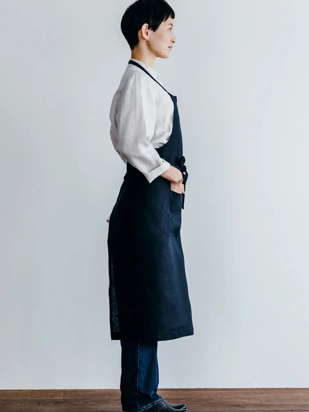 A side profile shows the comfortable fit and functional pocket of the Linen Full Apron in Navy from Fog Linen Work | Twentyseven Toronto