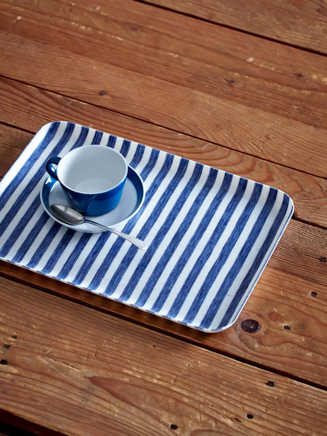 Linen Tray (M) - White Blue Stripe from Fog Linen Work is shown on a rustic wooden table holding a matching blue espresso cup and saucer | Twentyseven Toronto