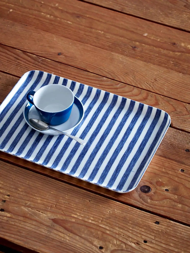 Linen Tray (M) - White Blue Stripe from Fog Linen Work is shown on a rustic wooden table holding a matching blue espresso cup and saucer | Twentyseven Toronto