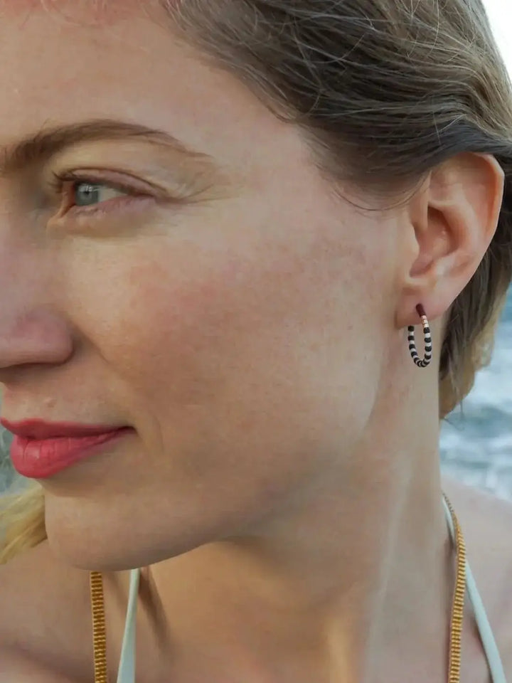 A close-up shot shows a person wearing a beaded small hoop earring, a lifestyle view of the Little Colorloop Earring from Alice Rise Jewelry | Twentyseven Toronto