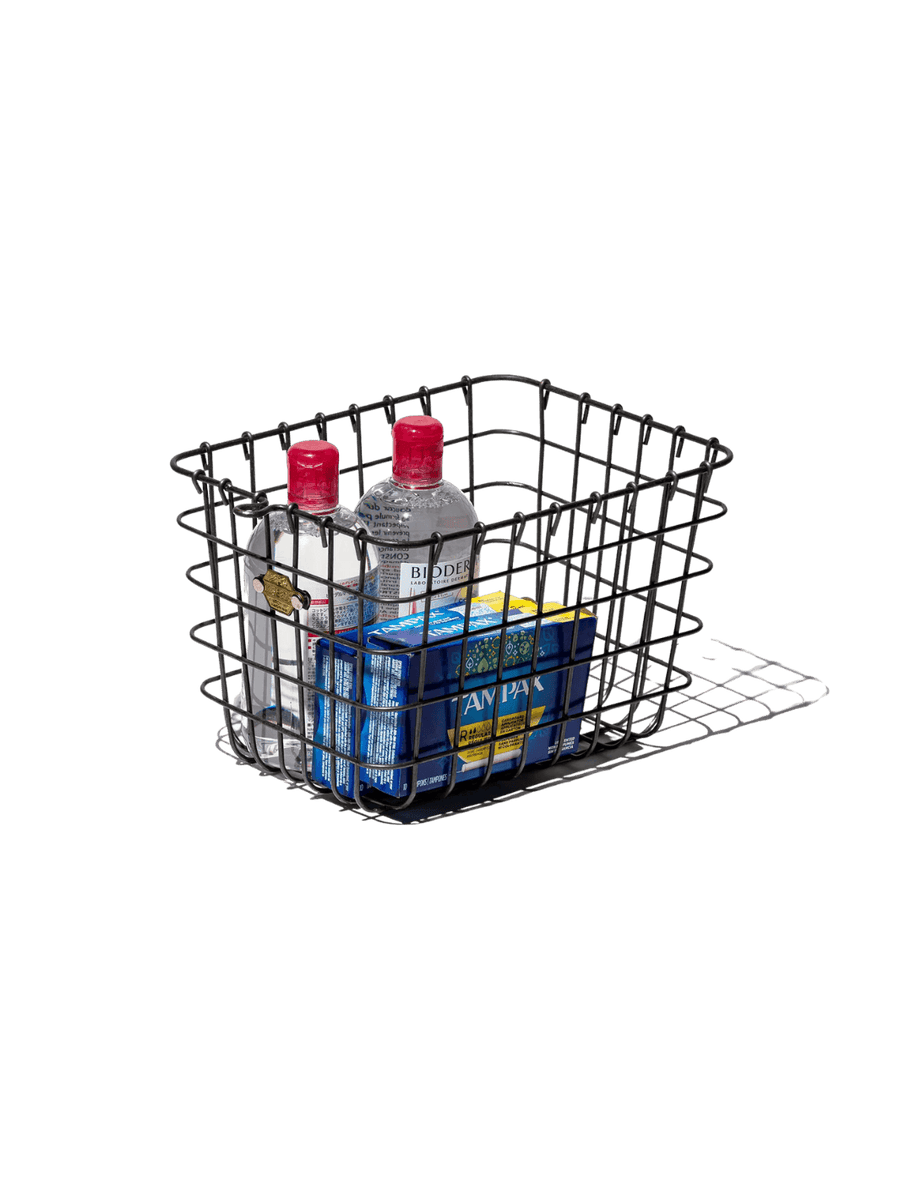 The Locker Basket - Medium from Puebco is holding personal care products and two clear bottles with red caps | Twentyseven Toronto