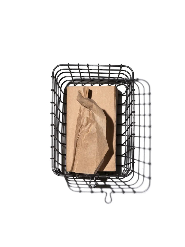 A top-down view captures the Locker Basket - Medium from Puebco containing a neatly wrapped brown paper package | Twentyseven Toronto