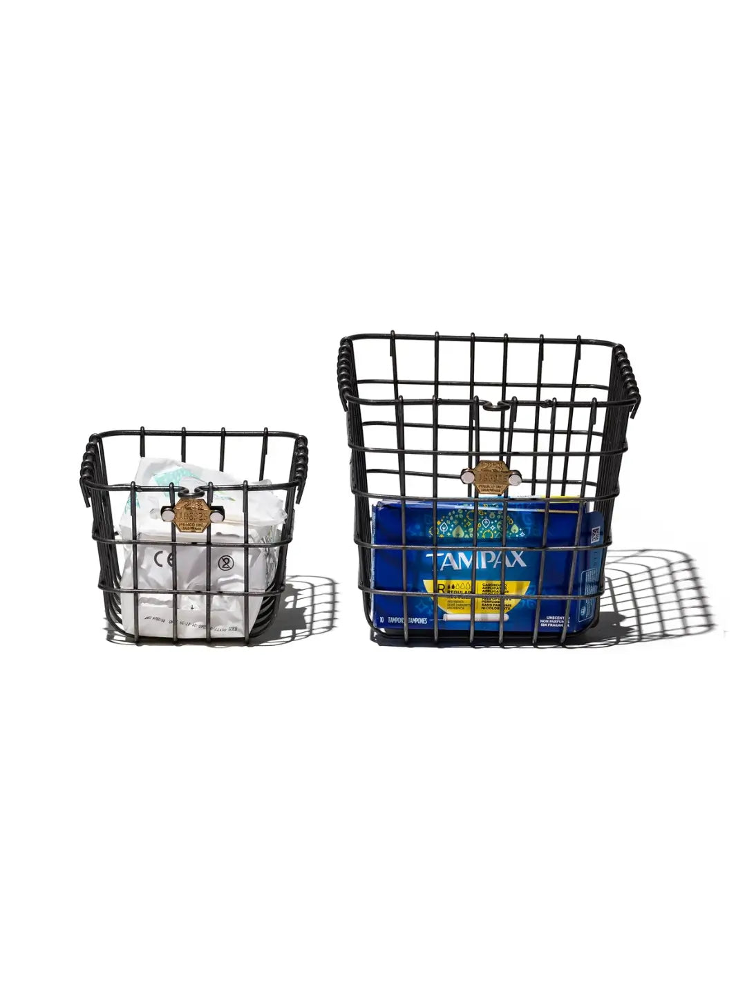 Two sizes of the industrial-style Locker Basket - Small from Puebco are shown side-by-side filled with personal care items against a white background | Twentyseven Toronto