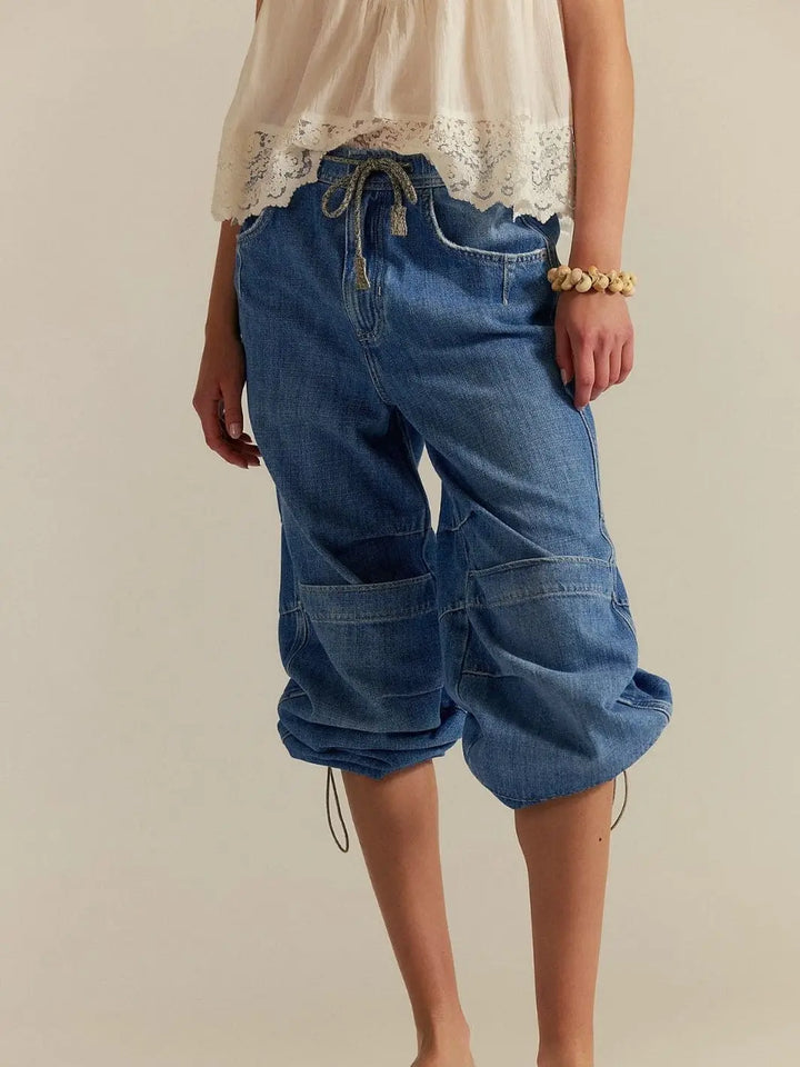 A front view shows the drawstring tie waist and the unique adjustable cuffs pulled up to create a cropped look on the Free People Logan Cinched Cargo Jeans - Harper | Twentyseven Toronto
