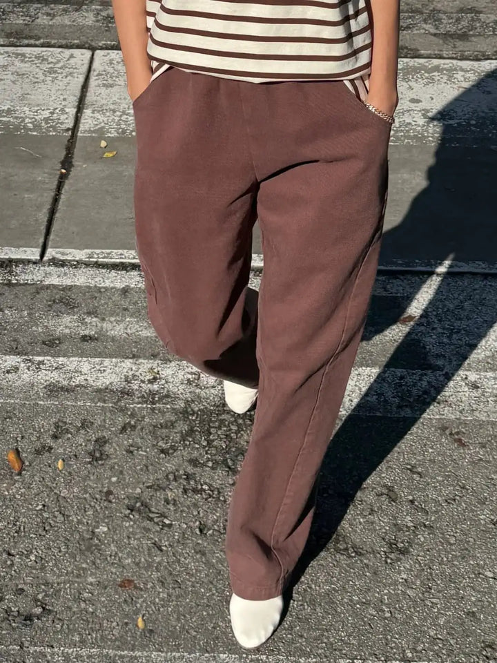 Person wearing brown 'Long Arc Pants' in 'Chocolate' and a striped shirt from Le Bon Shoppe on a street | Twentyseven Toronto