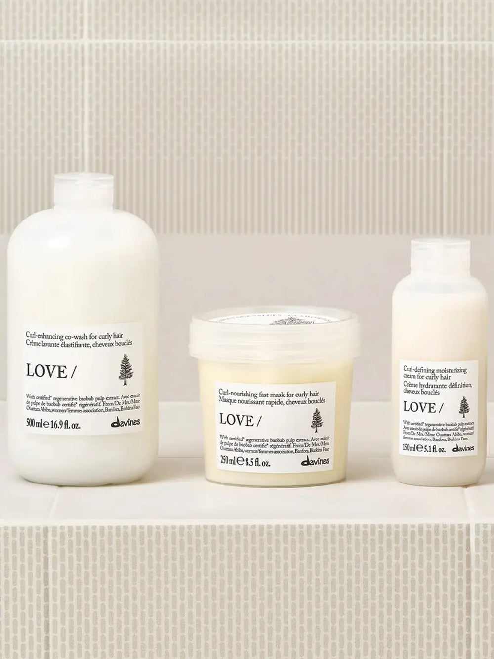 A product lineup photo shows the Davines LOVE CURL Co-Wash bottle positioned on a tiled shelf alongside its matching curl-nourishing fast mask and curl-defining moisturizing cream | Twentyseven Toronto