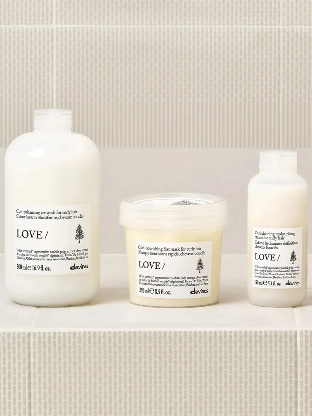 A product lineup photo shows the Davines LOVE CURL Co-Wash bottle positioned on a tiled shelf alongside its matching curl-nourishing fast mask and curl-defining moisturizing cream | Twentyseven Toronto