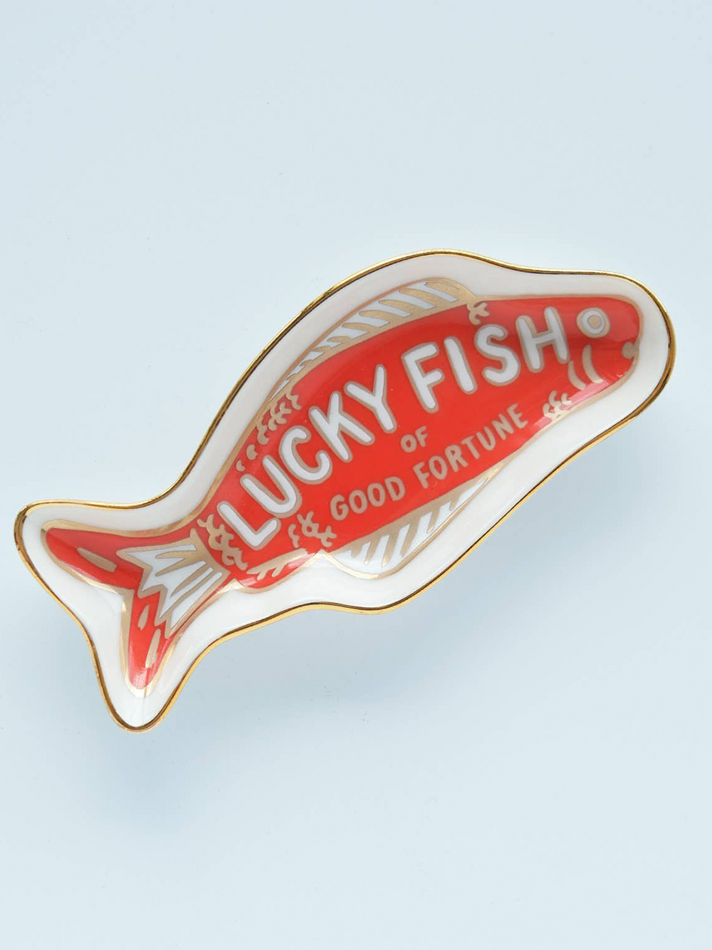 Angled view of the Idlewild Co. Fortune Fish ceramic trinket dish with a red lucky fish illustration, white porcelain border and delicate gold detailing | Twentyseven Toronto