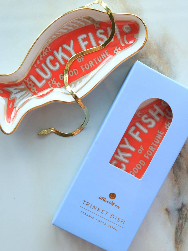Idlewild Co. Fortune Fish porcelain trinket dish styled with a gold bracelet and blue gift box, featuring a red fish illustration and gold accents | Twentyseven Toronto