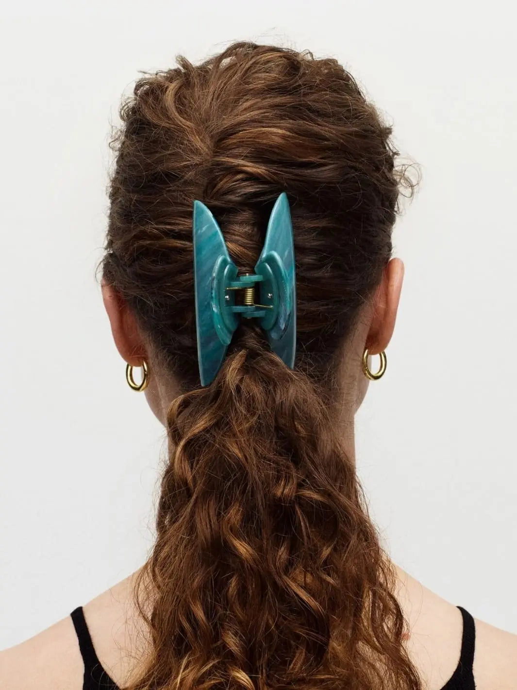 Person with a teal hair clip from MACHETE in their hair against a white background | Twentyseven Toronto
